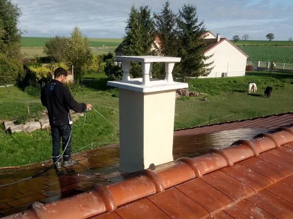 Nettoyage d'une toiture en tuiles autour d'une souche de cheminée