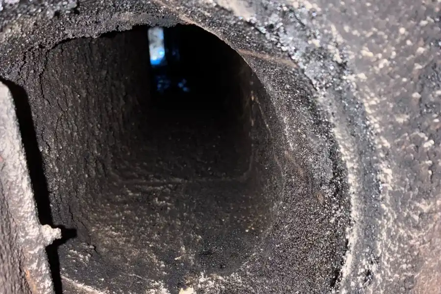 Intérieur d'un conduit de cheminée tapissé de bistre noir et croûteux, avant débistrage